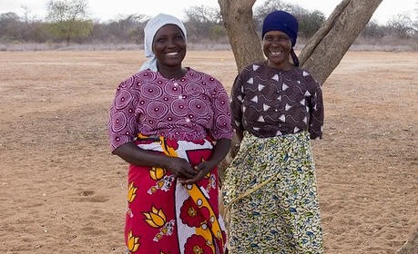 Two women stand under a tree